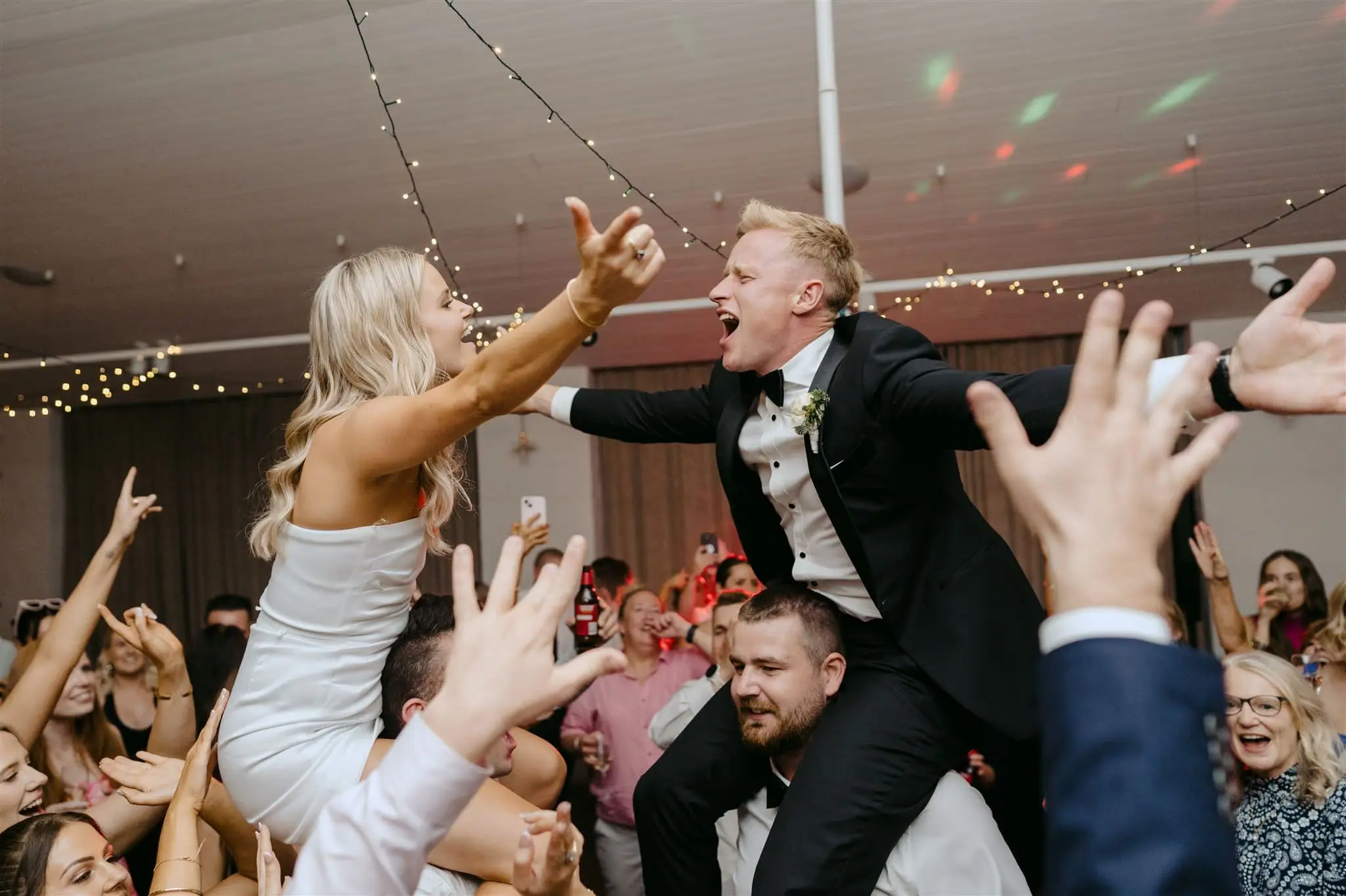 Country Victoria couple lifted by their guests on the dance floor