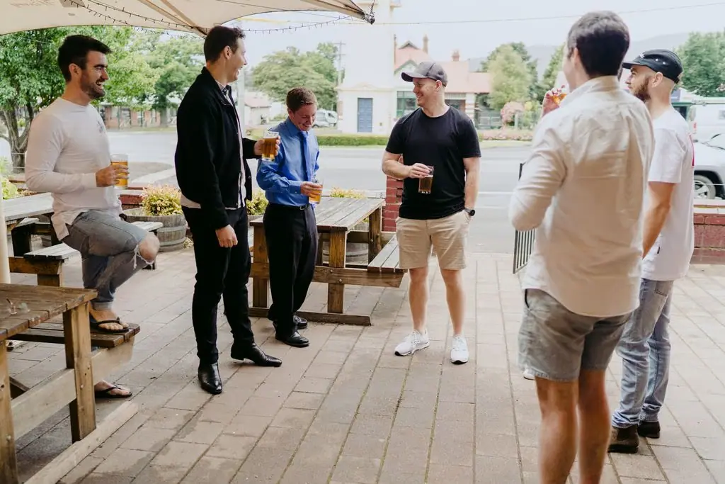 Men chatting with drinks on a covered terrace.